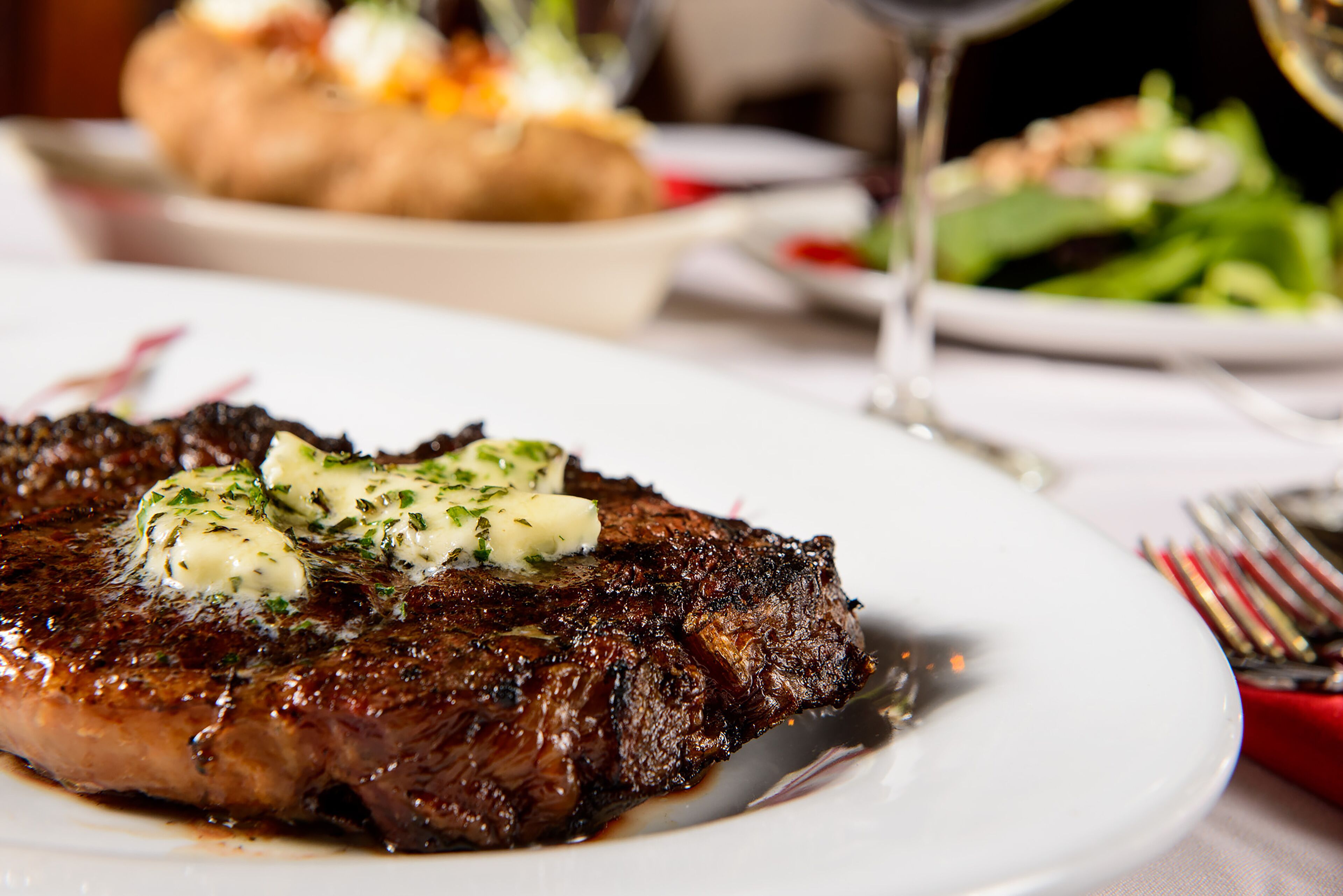 Un steak nappé de beurre et d’herbes, servi dans une assiette.