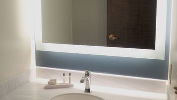 A bathroom with a large mirror, a sink, and a door.