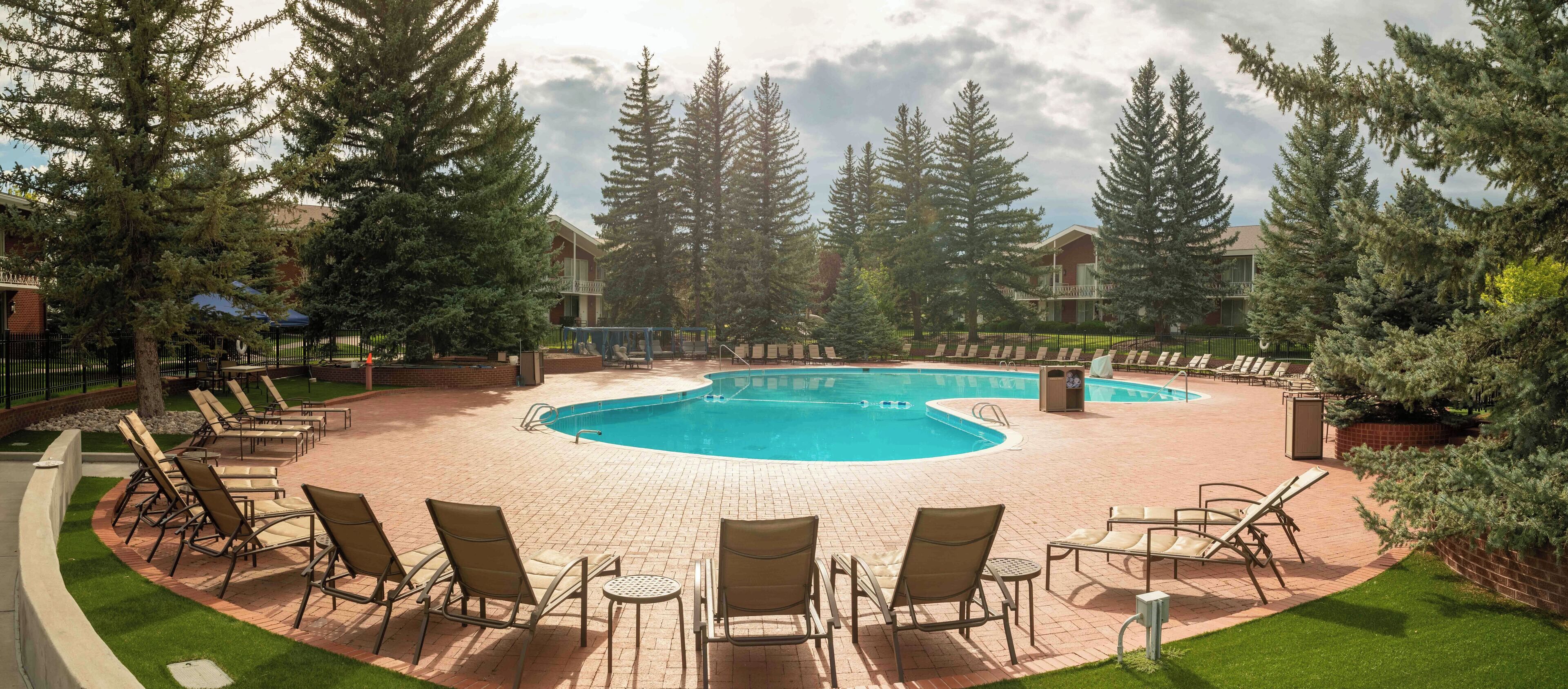 A circular outdoor swimming pool with lounge chairs and a brick patio.