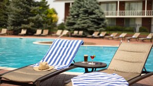A poolside area with lounge chairs, a pool, and a building in the background. - Little America Cheyenne (Cheyenne)