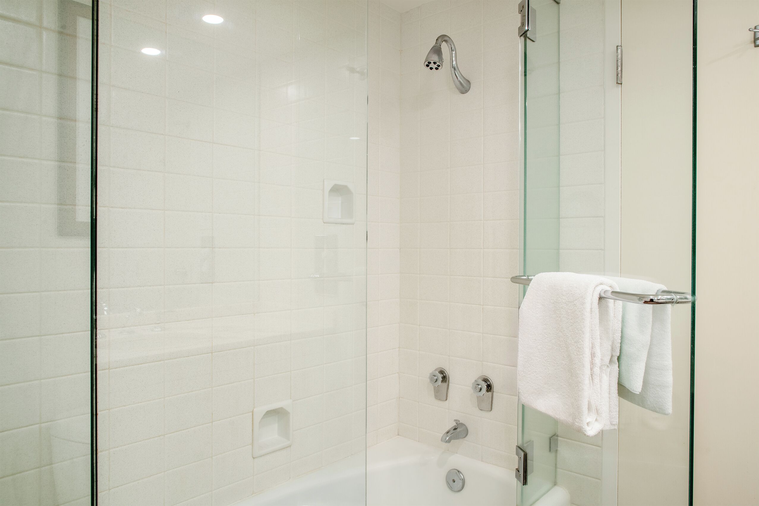 Un baño moderno con ducha acristalada, bañera acristalada y váter acristalado.