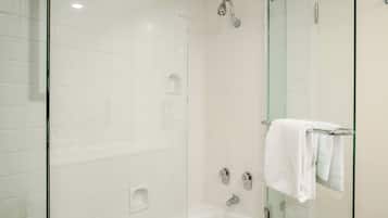 Un baño moderno con ducha acristalada, bañera acristalada y váter acristalado.