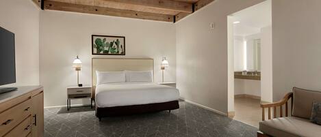 A bedroom with a bed, bedside tables, a TV, a sofa, and a small table.