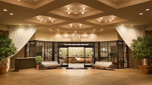 A hotel lobby with a reception desk, seating area, and a large sign reading "DOUBLETREE RESORT".