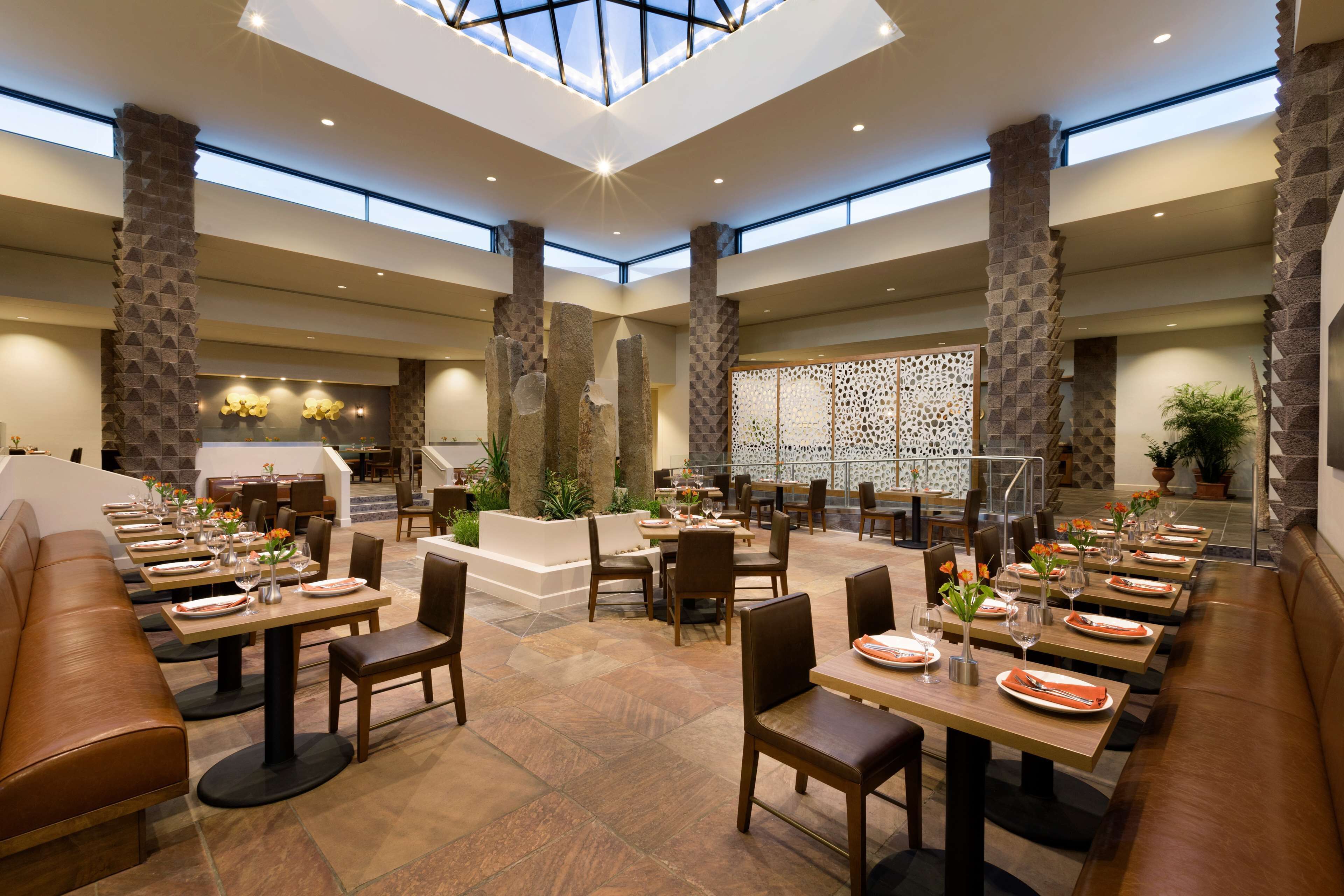 A spacious indoor dining area with high ceilings, stone pillars, and a central seating area.