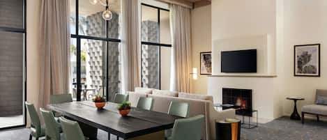 Una sala de estar moderna con comedor, ventanas amplias, chimenea y televisor de pantalla plana.
