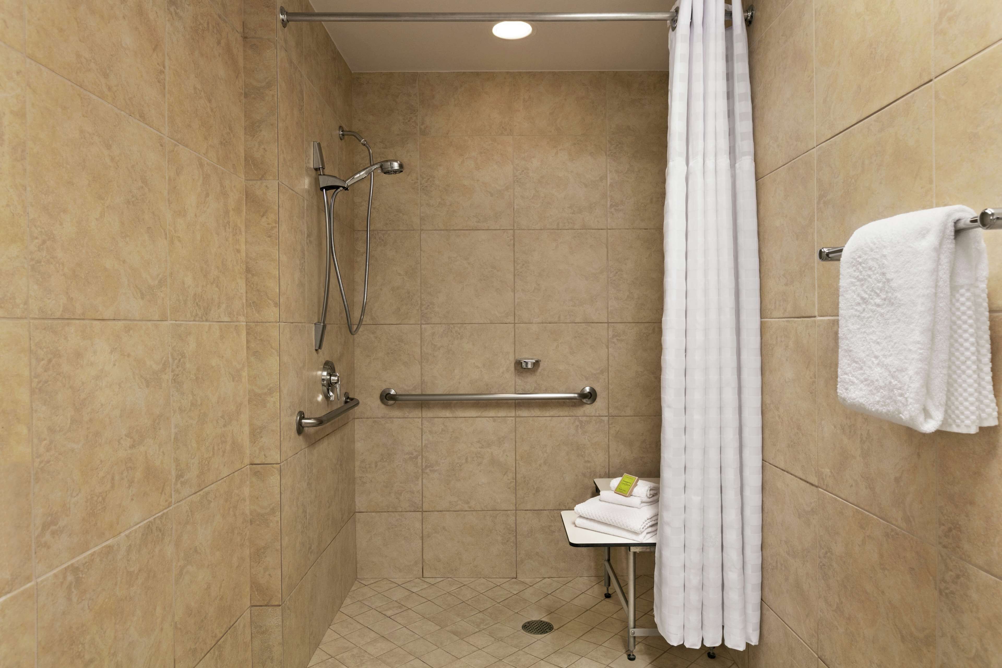A shower area with a grab bar, a towel rack, and a small table with towels.