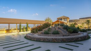 A hotel with a stone facade, a covered patio area, and a landscaped garden with a stone pathway.