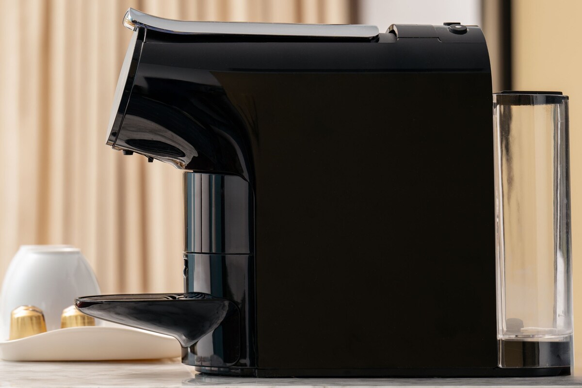 Una macchina da caffè con serbatoio dell'acqua e una tazza su un tavolo.