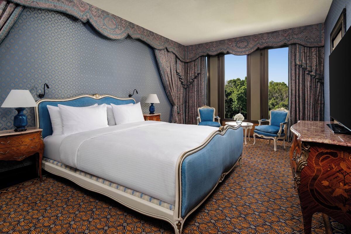 A hotel room with a large bed, two chairs, a desk, and a TV.