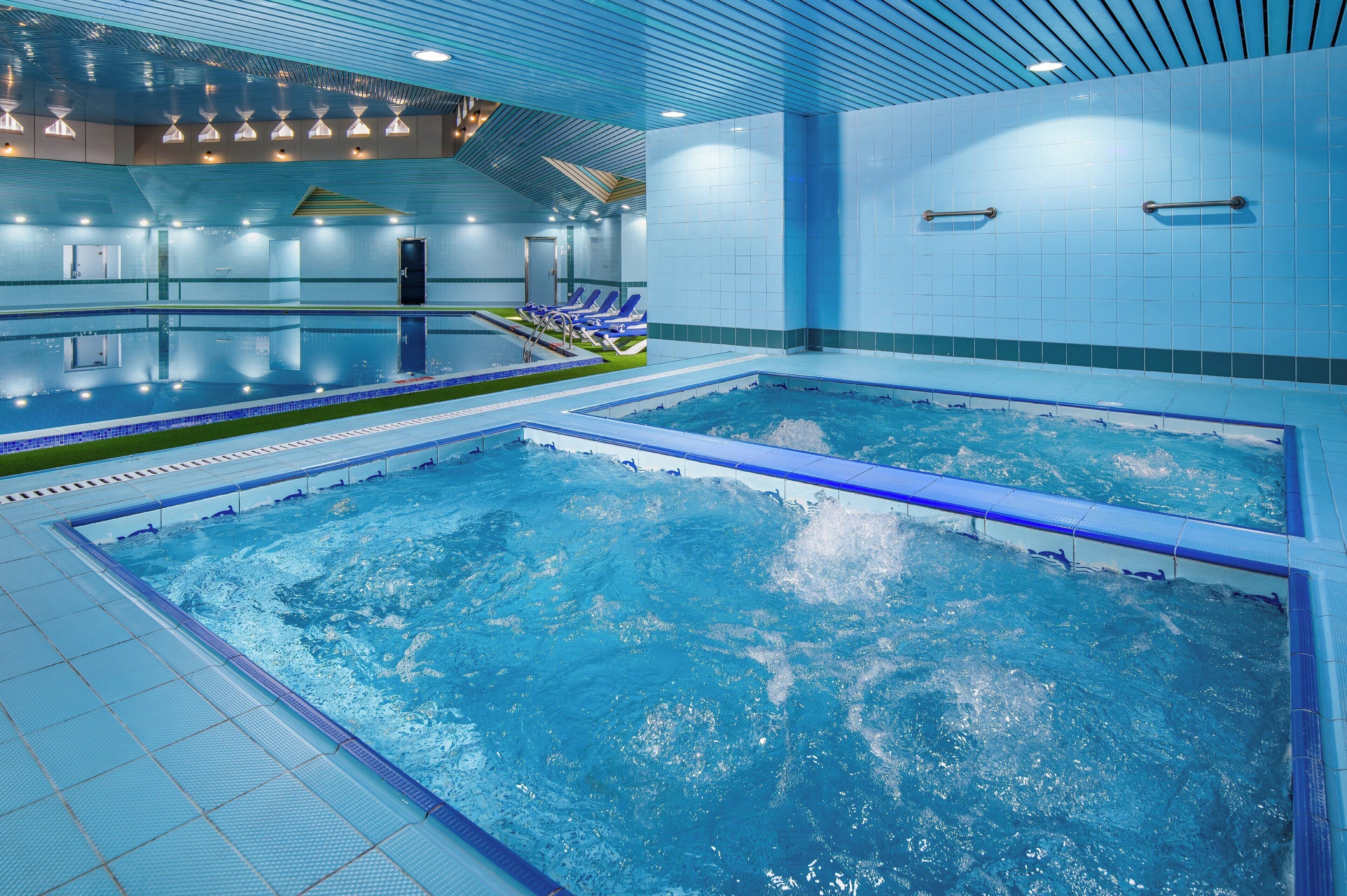 A large indoor swimming pool with multiple lanes, a changing room, and a reception area.