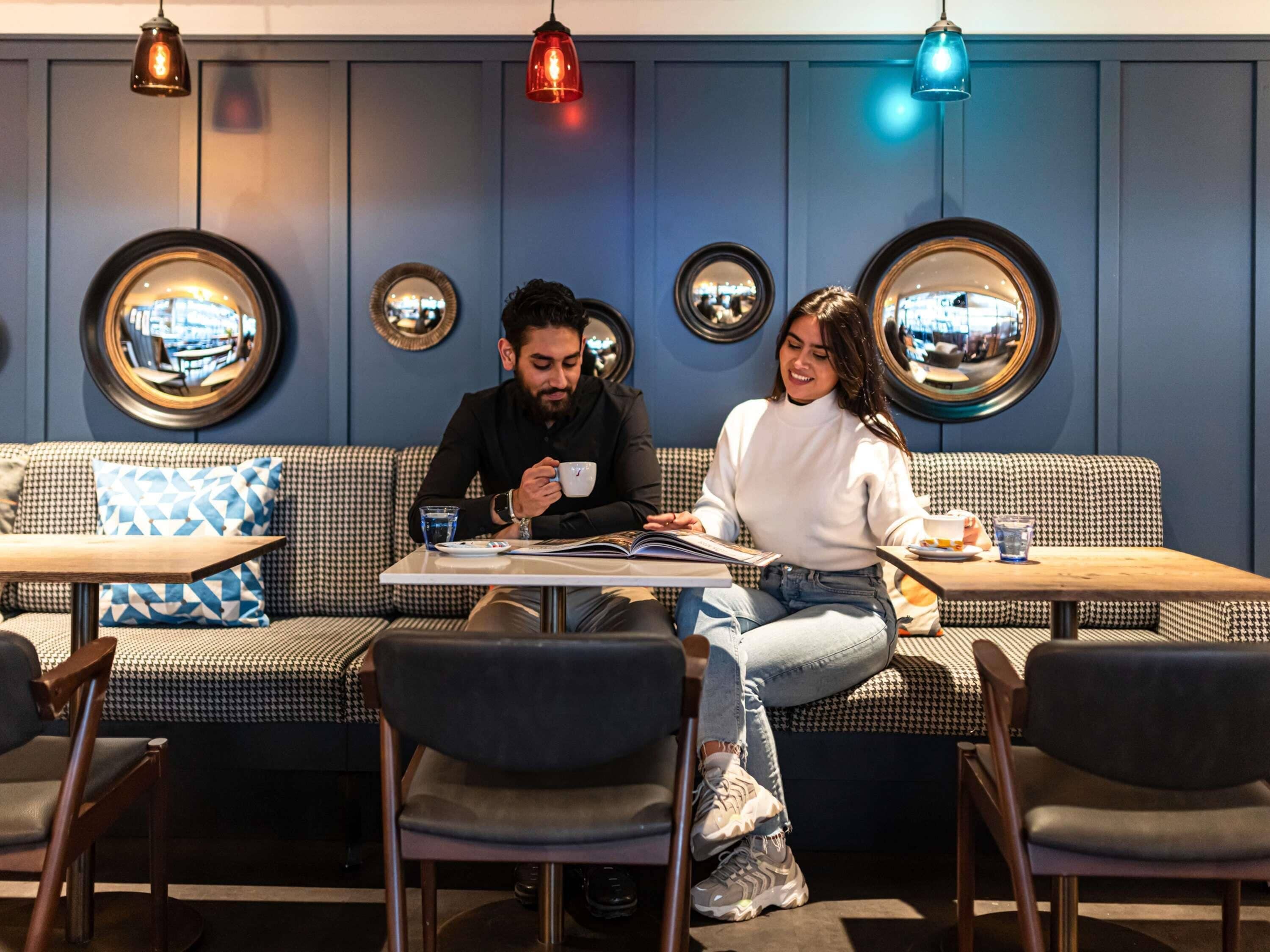 A cafe with a checkered sofa, round mirrors, and pendant lighting.