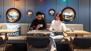 A cafe with a checkered sofa, round mirrors, and pendant lighting.