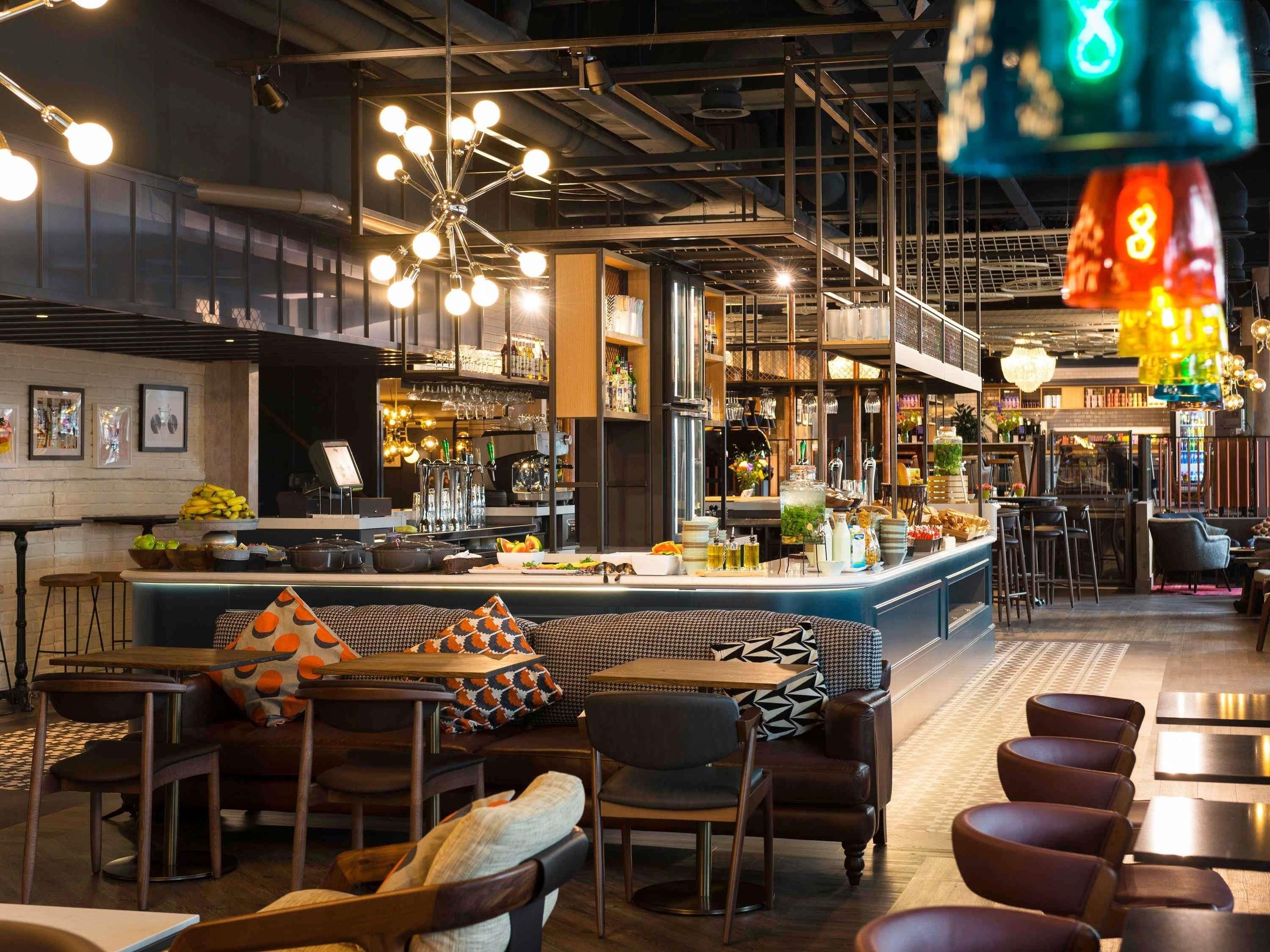 Un espace bar avec un comptoir, des tabourets et un coin salon agrémenté de coussins à motifs.