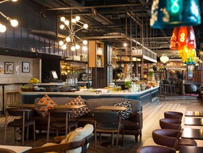 Zona de bar con mostrador, taburetes y asientos con cojines estampados.
