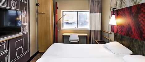 A hotel room with a bed, desk, chair, TV, wardrobe, and a window with a view.
