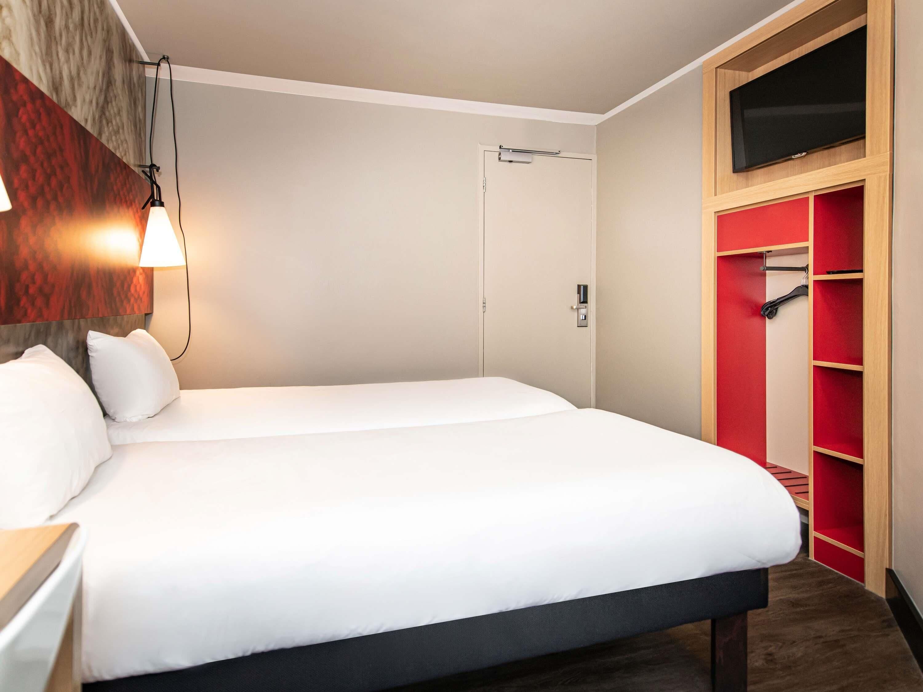 Una habitación de hotel con una cama, un armario y una televisión.