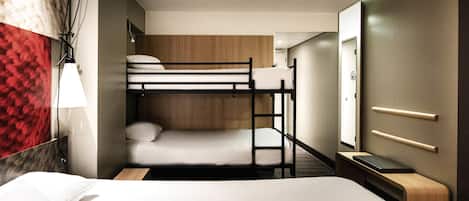 Habitación con literas, cabecero de madera, mesita de noche, lámpara y espejo.
