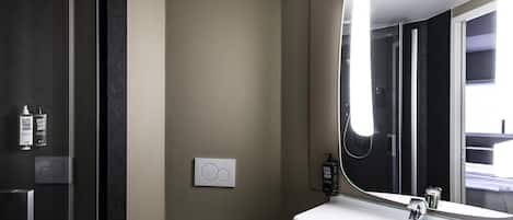 Un baño moderno con un espejo grande, inodoro y zona de ducha.