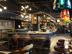 Zona de bar con mostrador, taburetes y un espacio de asientos con cojines estampados.