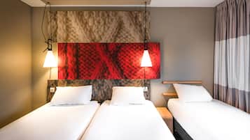 Une chambre d’hôtel avec deux lits, une grande œuvre d’art abstraite accrochée au mur et un rideau sur le côté droit.