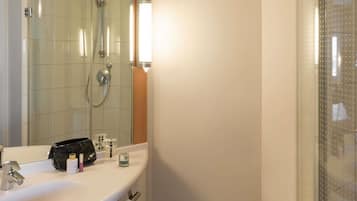 A bathroom with a sink, mirror, and shower.