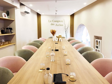 A conference room with a long table, chairs, and a sign reading 'Le Comptoir des Arches'.