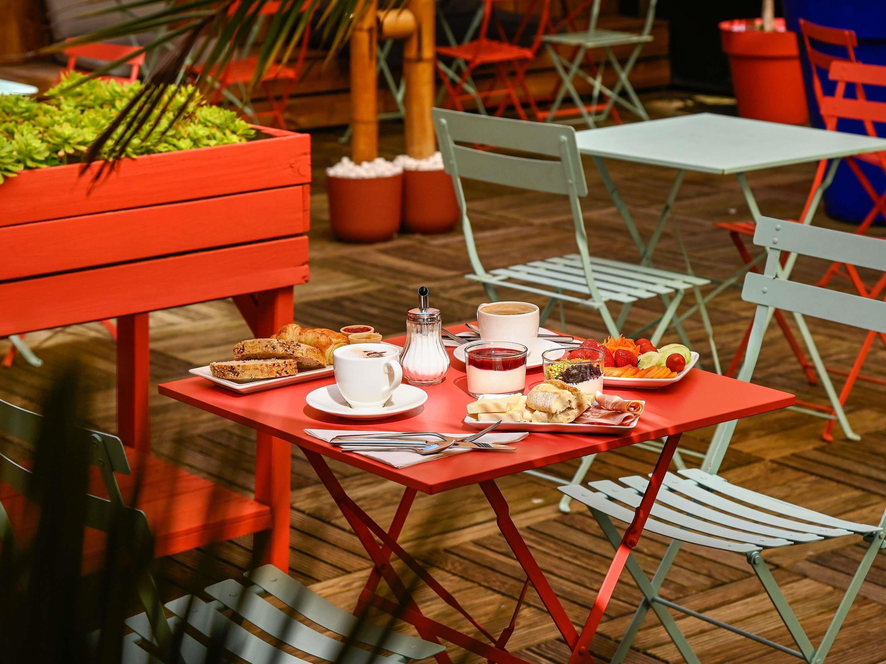 A dining table with food, a coffee cup, and a glass of red drink.