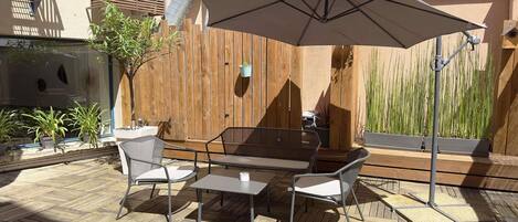 Un patio al aire libre con mesa y sillas, una sombrilla grande y una valla de madera.