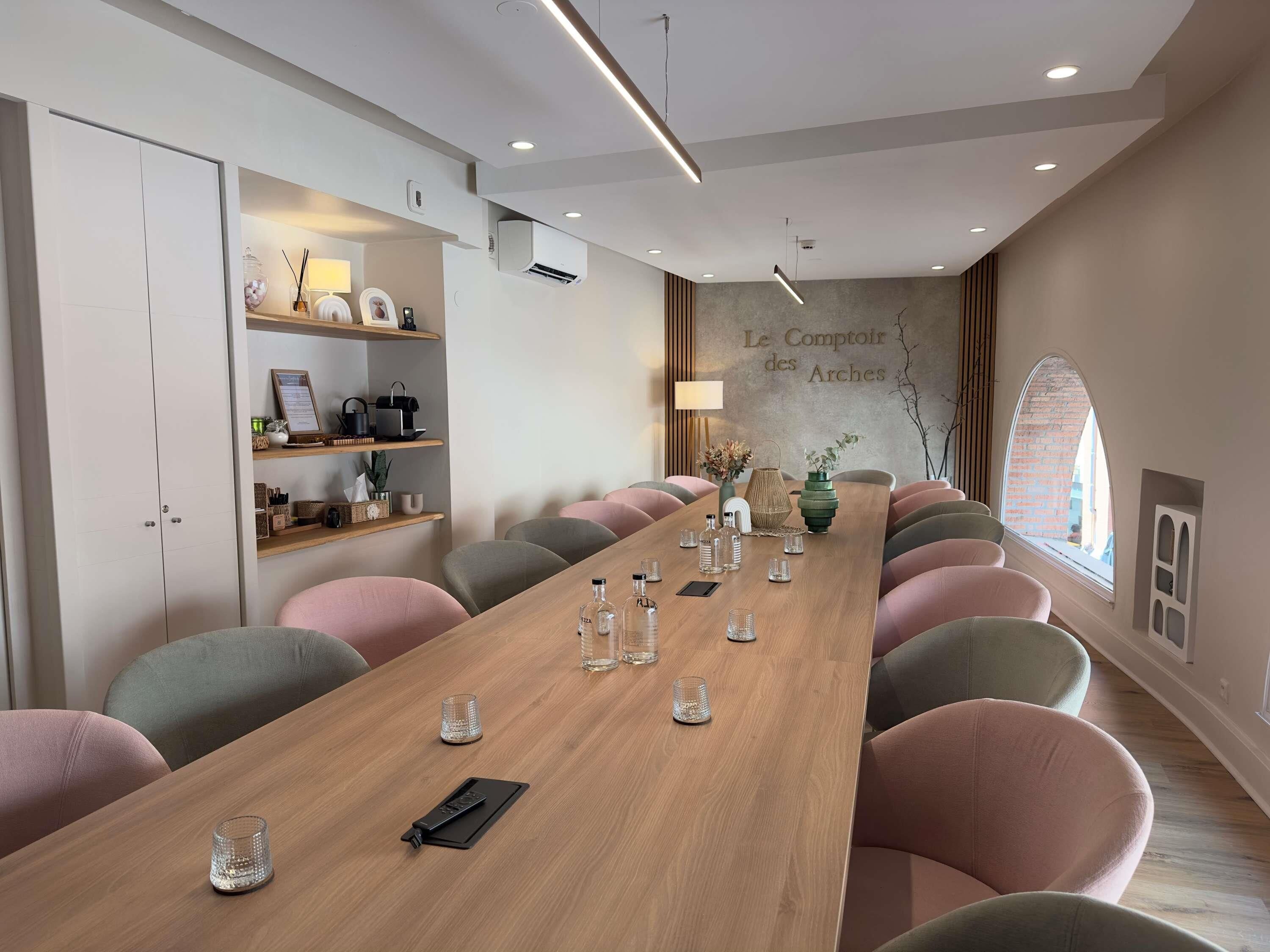 A conference room with a long table, chairs, and a wall with a sign.