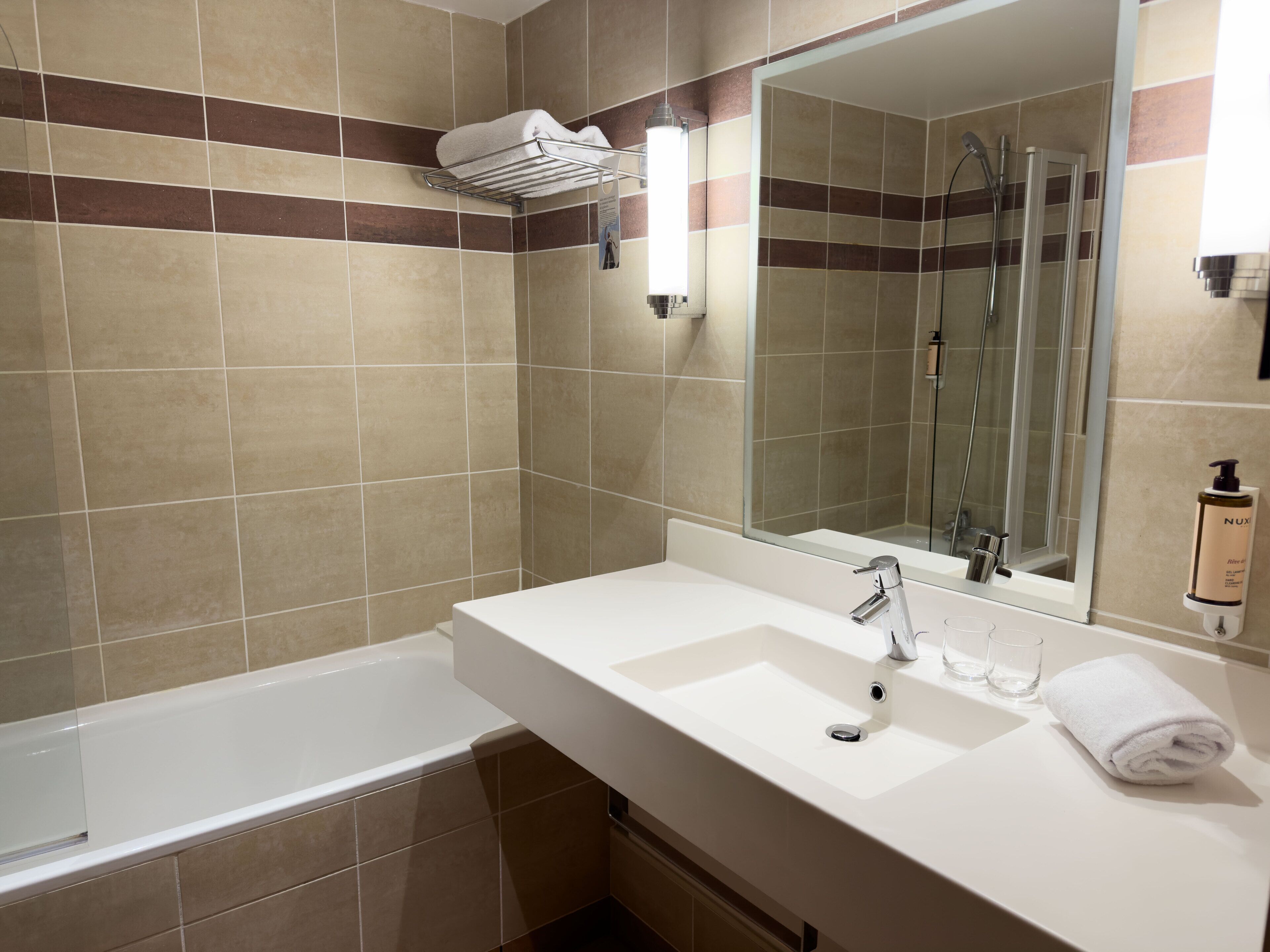 A modern bathroom with a bathtub, a sink, and a large mirror.
