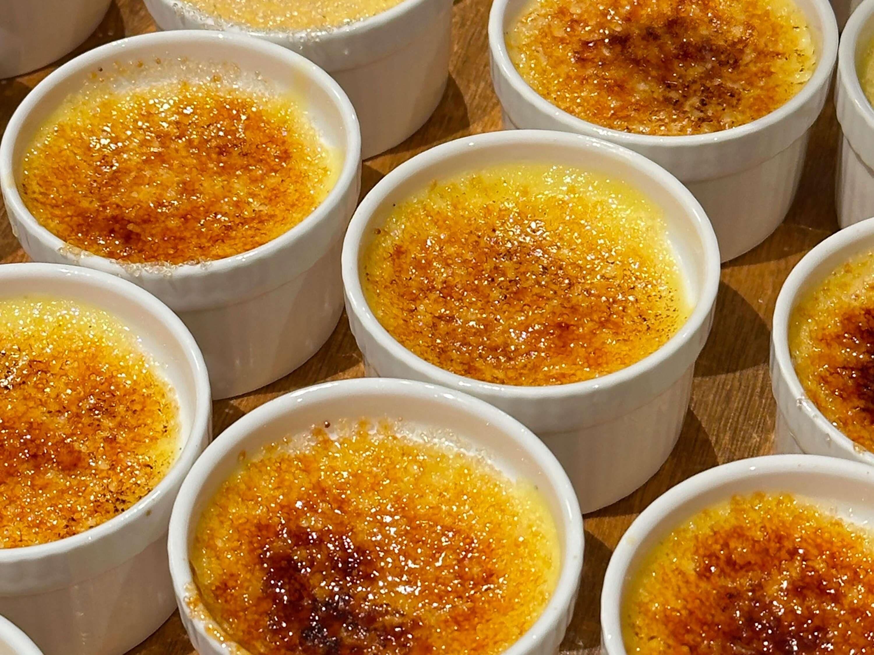 Multiple white ramekins with a golden-brown top, likely containing crème brûlée.