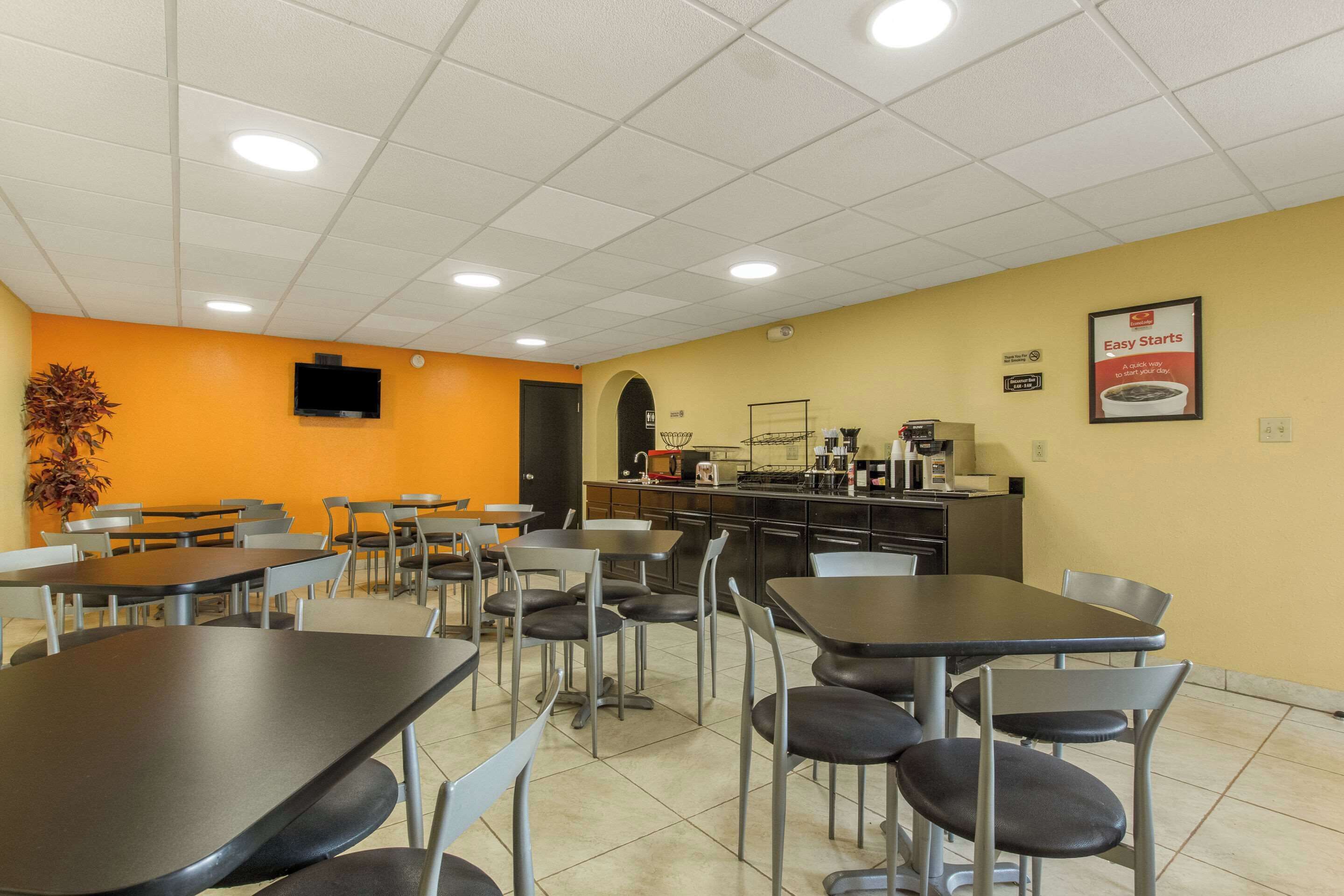 Une cafétéria avec des tables et des chaises, un téléviseur fixé au mur et un panneau indiquant : « Débuts faciles ».