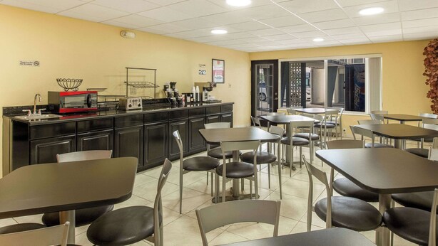 A restaurant with a kitchen area, tables, and chairs. - Econo Lodge Fort Knox (Radcliff)