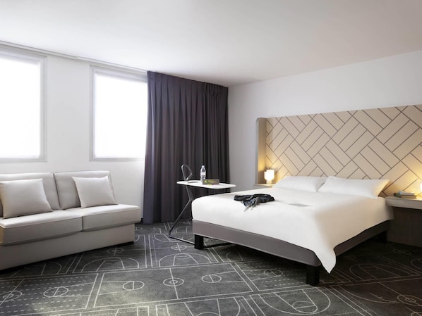 A hotel room with a bed, a sofa, a small table, and a window with curtains. - ibis Styles Paris Massena Olympiades (Paris)