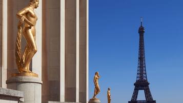 A statue of a woman in a dress, a smaller statue, and the Eiffel Tower.