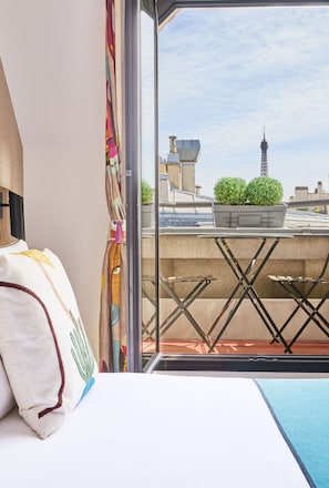 Ein Zimmer mit Bett, Fenster und Blick auf Gebäude und einen Turm.