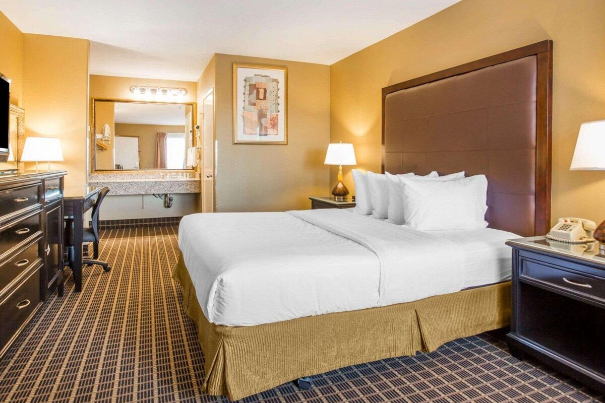 Ett hotellrum med en stor säng, en byrå, en spegel och en telefon.