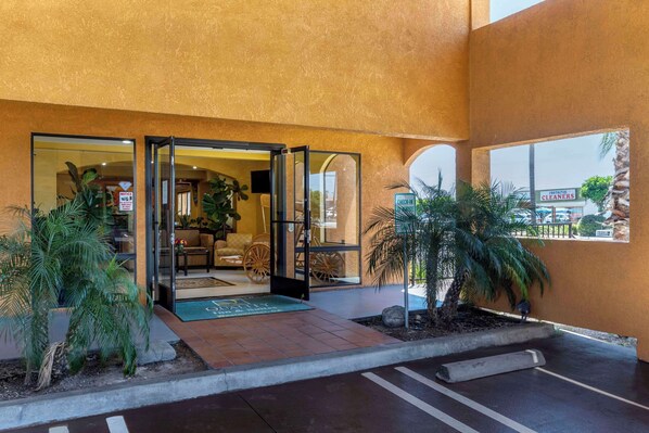 A hotel entrance with a glass door, indoor seating area, and a view of the street. - Quality Inn & Suites Westminster Seal Beach (Westminster)