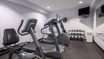 A gym with stationary bikes, treadmills, and a rack of dumbbells.