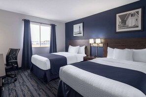 Habitació d'hotel amb dos llits, una taula, una cadira i una finestra amb cortines.