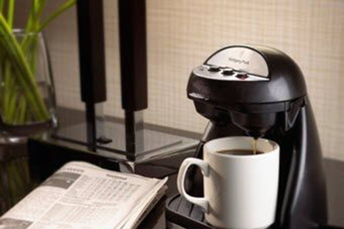 En kaffemaskine på et bord med en kop kaffe og en avis.