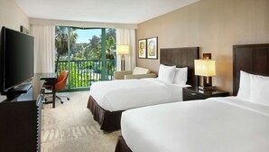 A hotel room with two beds, a TV, a desk, and a chair.