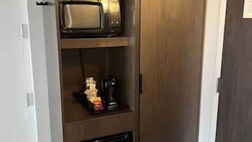 Un armario con microondas, cafetera y un refrigerador pequeño.