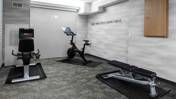 A gym with stationary bikes, a treadmill, and a bench.