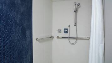 A shower with a handheld showerhead and a wall-mounted faucet.