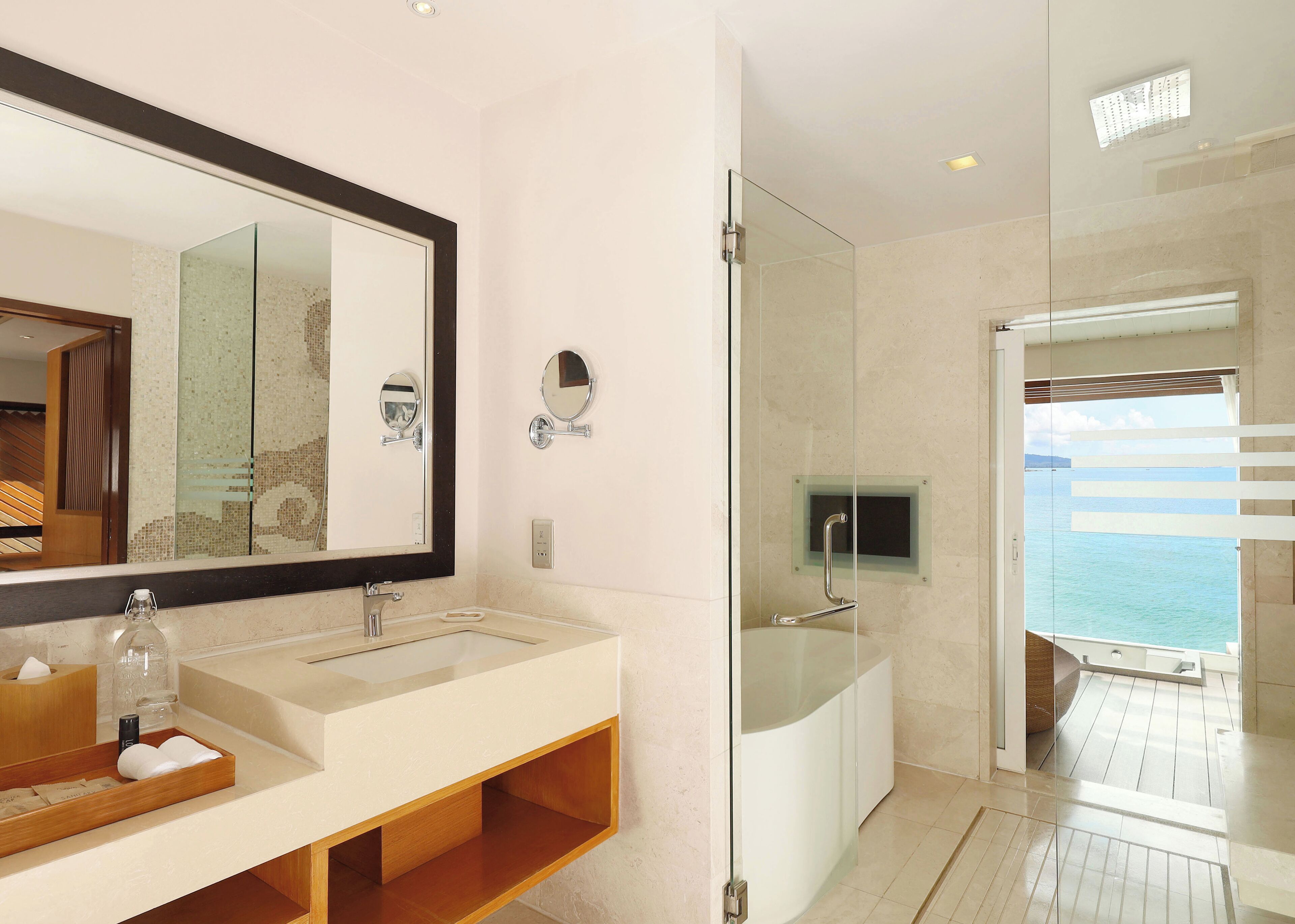 A modern bathroom with a large mirror, dual sinks, and a glass-enclosed shower.