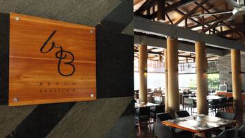A restaurant interior with a wooden sign reading "BEACH BRASSERIE" and a modern ceiling with exposed beams.