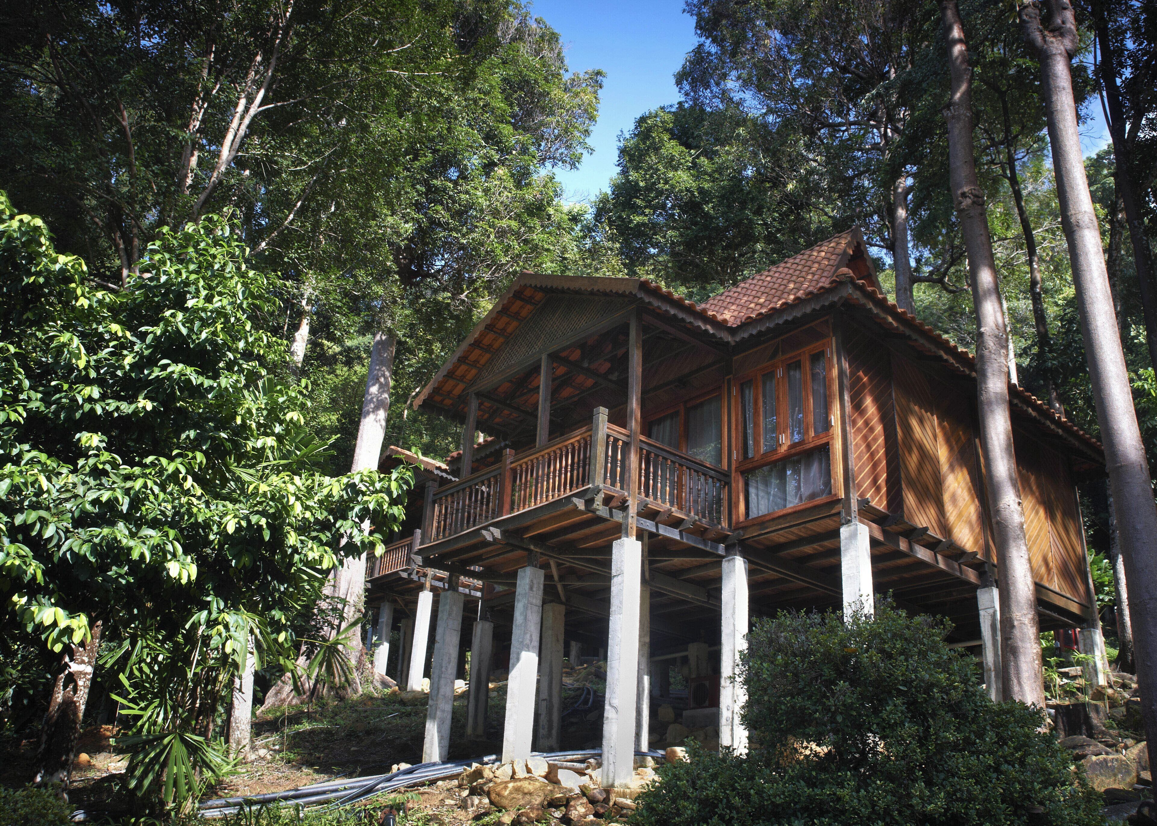 Une cabane en bois dotée d’un balcon, entourée d’arbres.