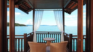 A wooden deck with wicker chairs and a table, overlooking a calm sea with distant land. - Berjaya Langkawi Resort (Langkawi)